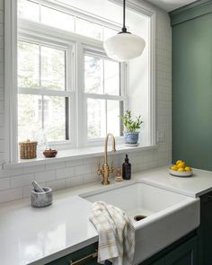 a white kitchen sink sitting under a window next to a counter top with dishes on it