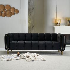 a black couch sitting on top of a white floor next to a wall with gold accents