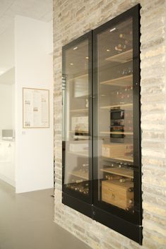 an empty wine cellar with glass doors and brick wall