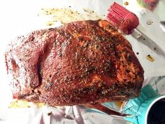 a large piece of meat sitting on top of foil next to a knife and fork