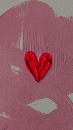 a red heart shaped object on top of pink paint