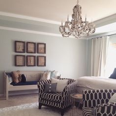 a living room filled with furniture and a chandelier hanging from the ceiling over a bed