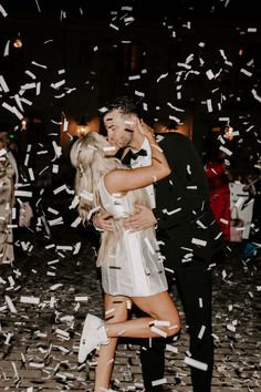 a man and woman kissing in front of confetti