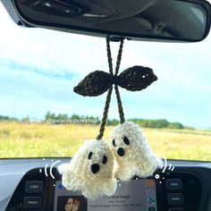 two crocheted dogs hanging from the dashboard of a car in front of a rear view mirror