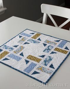 a white table with a blue and yellow quilt on it