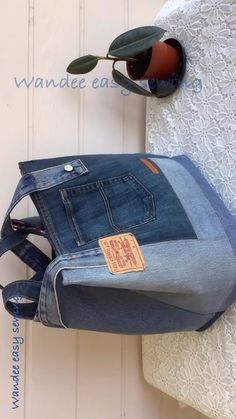 an old pair of jeans hanging on the wall next to a flower pot and sunglasses