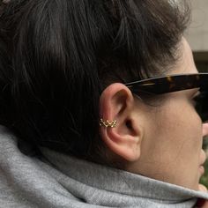 a close up of a person wearing sunglasses and a scarf with ear piercings on their ears