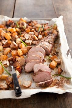 meat and potatoes are on a tray with a pair of tongs next to it