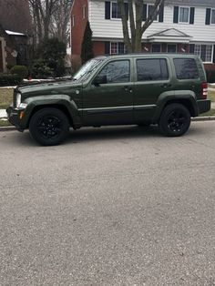 a green jeep is parked in front of a house