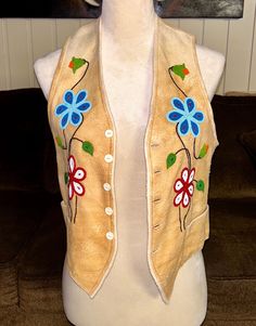 a white mannequin wearing a tan vest with blue flowers on it