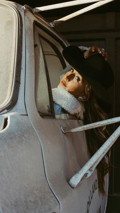 a woman wearing a hat leaning out the window of a car