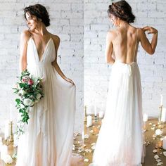 the back of a woman's wedding dress with flowers and candles in front of her