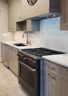 a kitchen with an oven, sink and clock on the wall above it's counter