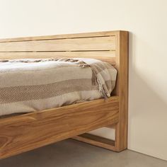 a wooden bed frame with a striped blanket on it's headboard and foot board