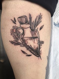 a tattoo on the leg of a woman with flowers in a bottle and leaves around it