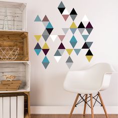 a white chair sitting in front of a wall with colorful triangles on it's side