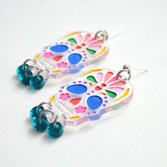 Clear acrylic laser cut earrings with a unique engraved Day of the Dead sugar skull pattern. The skull details are filled with blue, purple, green, yellow, red and pink acrylic paint. Below the skull hang small circle dangles in turquoise mirrored acrylic.- These acrylic pieces are engraved with my laser cutter and do not have resin.- Choose from stainless steel gold or silver ear wires and hardware.- Earrings are 2 inches long by 1.4 inches wide.- Earring backs are hypoallergenic stainless stee Skull Hanging, Small Circle, Laser Cut Earrings, Pink Acrylics, Ear Wires, Acrylic Earrings, Earring Backs, Sugar Skull, Clear Acrylic