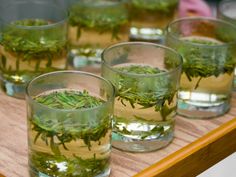 several glasses filled with water and herbs on a table