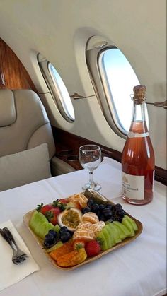 a tray with fruit and wine on an airplane