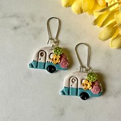 the earrings are decorated with colorful flowers and an old camper on it's side