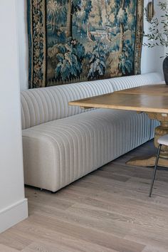 a room with a table, bench and tapestry on the wall