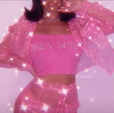 a woman wearing a pink crop top and skirt with sparkles on the bottom, standing in front of a white background