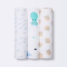 three baby swaddles with an octopus and seashells on them, one is blue