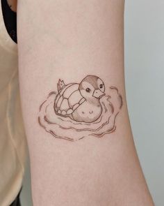 a woman's arm with a small tattoo of a turtle swimming in the water