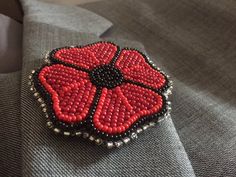 a red beaded poppy flower sitting on top of a gray suit lapel cover