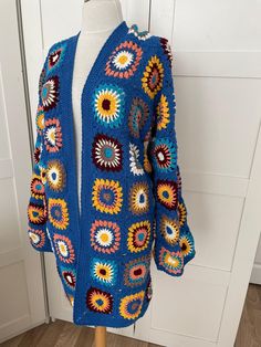 a blue crocheted cardigan with multicolored flowers on it