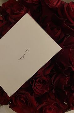 red roses and a white card with the word love you written on it