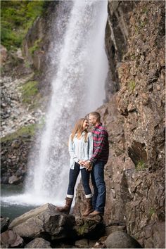 a man and woman standing in front of a waterfall