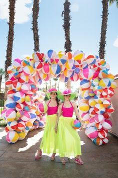 two women are standing in front of colorful balloons