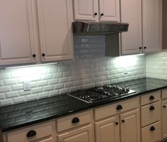 a stove top oven sitting inside of a kitchen next to white cabinets and counter tops