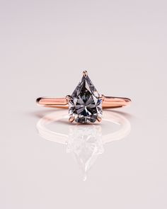 an engagement ring with a fancy diamond in the center on a reflective surface, reflecting light