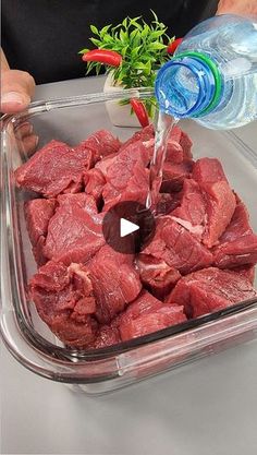 a person pouring water into a container filled with raw meat