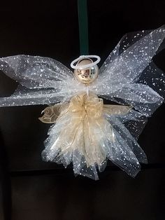 a white angel ornament hanging from a green ribbon on a black background with water droplets