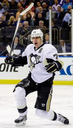 a hockey player in white jersey and black pants playing on the ice with his arms out