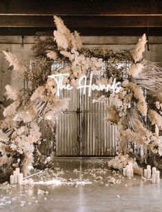 a floral arch with candles and flowers on the floor in front of an open door