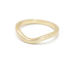 a gold ring with curved edges on a white background, the band is slightly bent