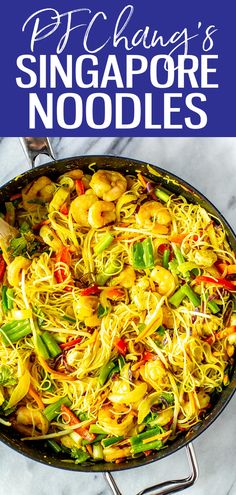 a pan filled with noodles and vegetables on top of a marble counter next to a blue sign