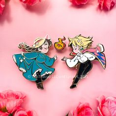 two anime pin badges sitting on top of pink paper next to red flowers and petals