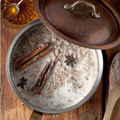 an overhead view of a pot with cinnamon sticks in it and spices on the side