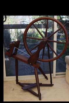 a wooden spinning wheel on display in front of a window