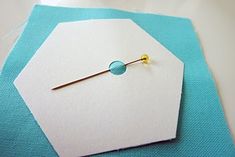 a piece of white paper with a pin on it sitting on top of a table