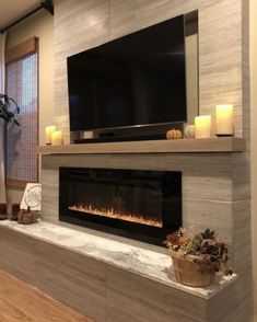 a living room with a fireplace and television mounted on the wall next to a window