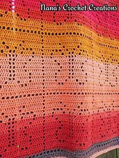 a colorful crocheted blanket is hanging on a wooden fence with it's edge