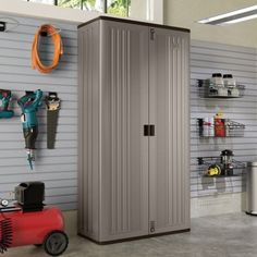 a storage cabinet in a garage with tools hanging on the wall