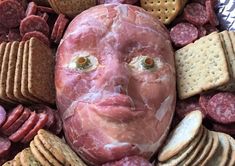 a face made out of meat surrounded by crackers and cheeses