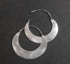 Super sleek silver hoop earrings handmade in Cairo using traditional silversmithing techniques. I've taken the shape of a typical Nubian or bedouin earring but have left it plain without the usual etched designs. This creates a clean, quite minimalist earring which is unusual and very wearable. They also catch the light beautifully. Available in 3 sizes - width 3.2cm, 4.5cm and 5.2cm Cairo hallmarks Small: Weight: 1.4gm Width: 3.2cm Length: 3.3cm Medium: Weight: 2.5gm Width: 4.5cm Length: 4.1cm Artisan Silver Dangle Hoop Earrings, Traditional Hammered Silver Earrings, Traditional Silver Hammered Earrings, Artisan Silver Round Hoop Earrings, Handmade Silver Round Hoop Earrings, Everyday Handmade Silver Hoop Earrings, Handmade Silver Hoop Earrings For Everyday, Artisan Small Hoop Sterling Silver Earrings, Artisan Silver Small Hoop Earrings